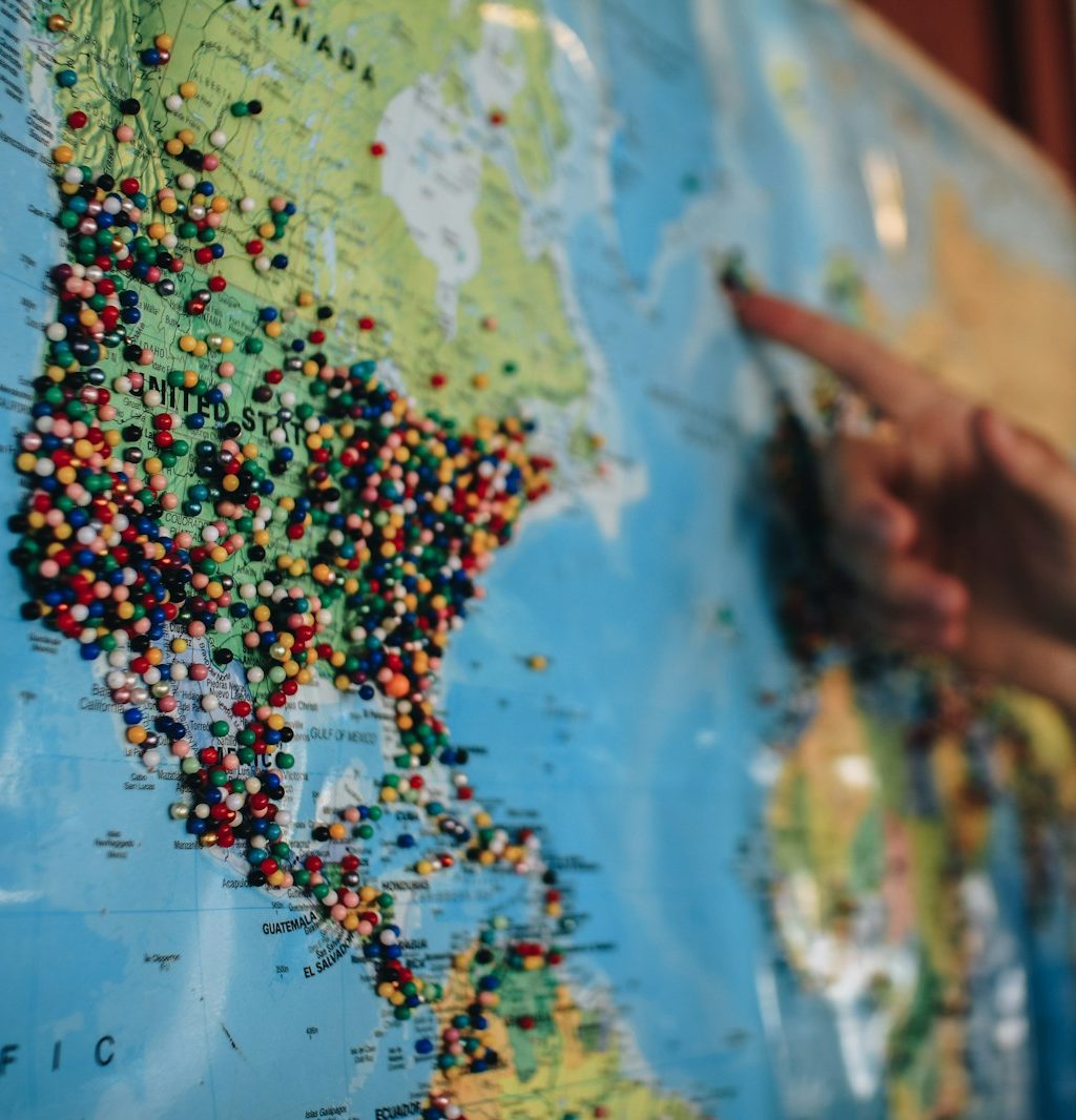 a person pointing at a map with pins on it
